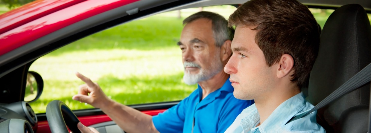 Jonge jongen achte het stuur in de auto met een oudere man ernaast
